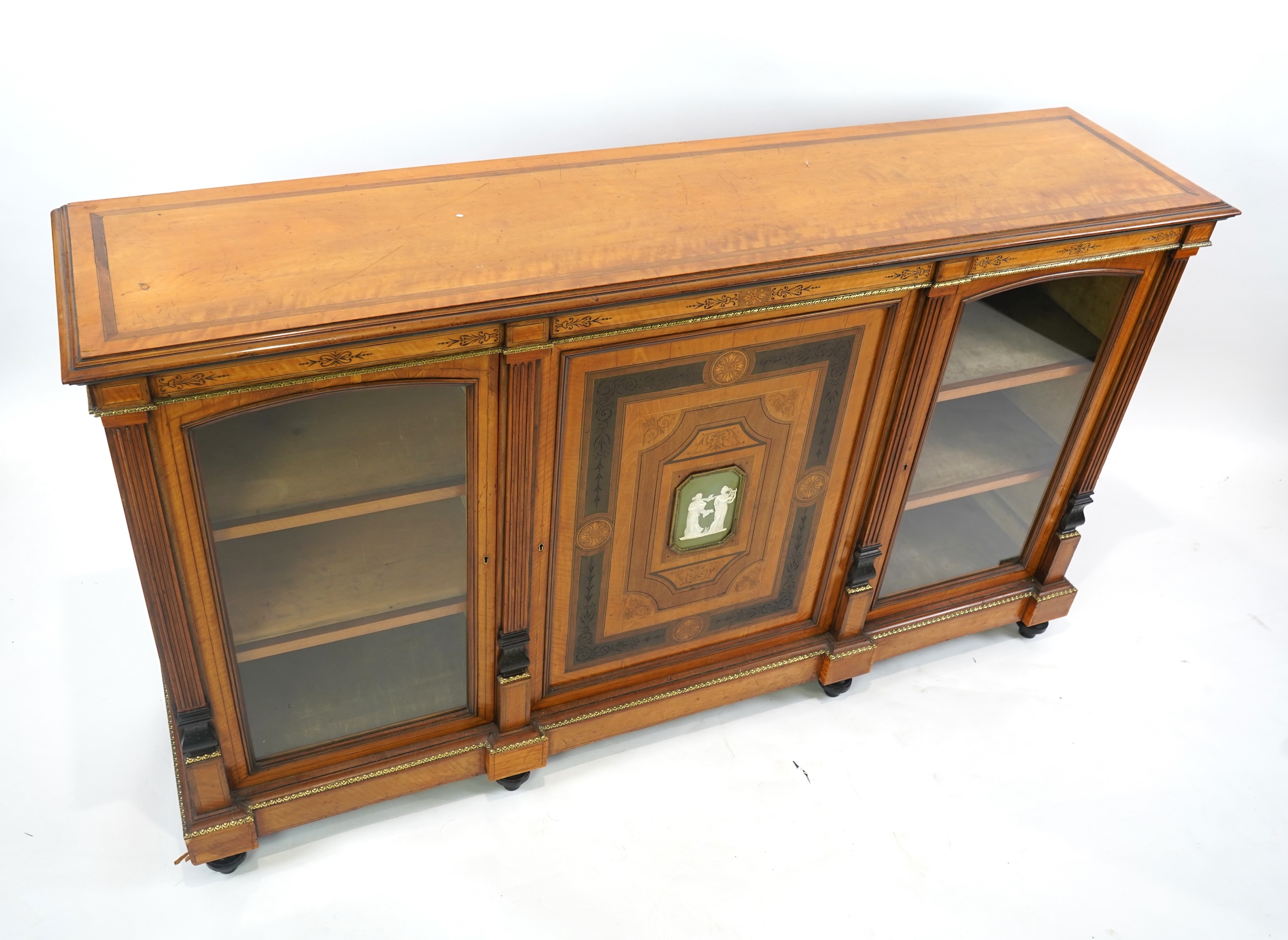 A Victorian marquetry inlaid and gilt metal mounted banded satinwood side cabinet, with anthemion carved frieze over a central door applied octagonal Wedgwood style green and white octagonal jasper plaque, flanked by gla